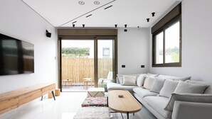 A modern living room with a sofa, a coffee table, and a TV mounted on the wall. - Luxury 2BR In Flea Market By Holiday Rentals (Tel Aviv-Yafo)