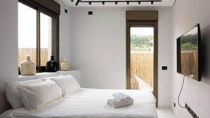 A modern bedroom with a large bed, a TV mounted on the wall, and a window overlooking a wooden deck. - Luxury 2BR In Flea Market By Holiday Rentals (Tel Aviv-Yafo)