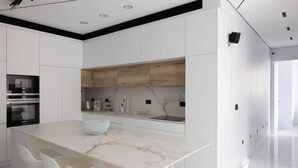 A modern kitchen with white cabinetry, a marble countertop, and a central island with seating. - Luxury 2BR In Flea Market By Holiday Rentals (Tel Aviv-Yafo)