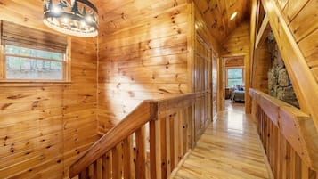 A wooden interior with a staircase, wooden walls, and a stone wall in the background.
