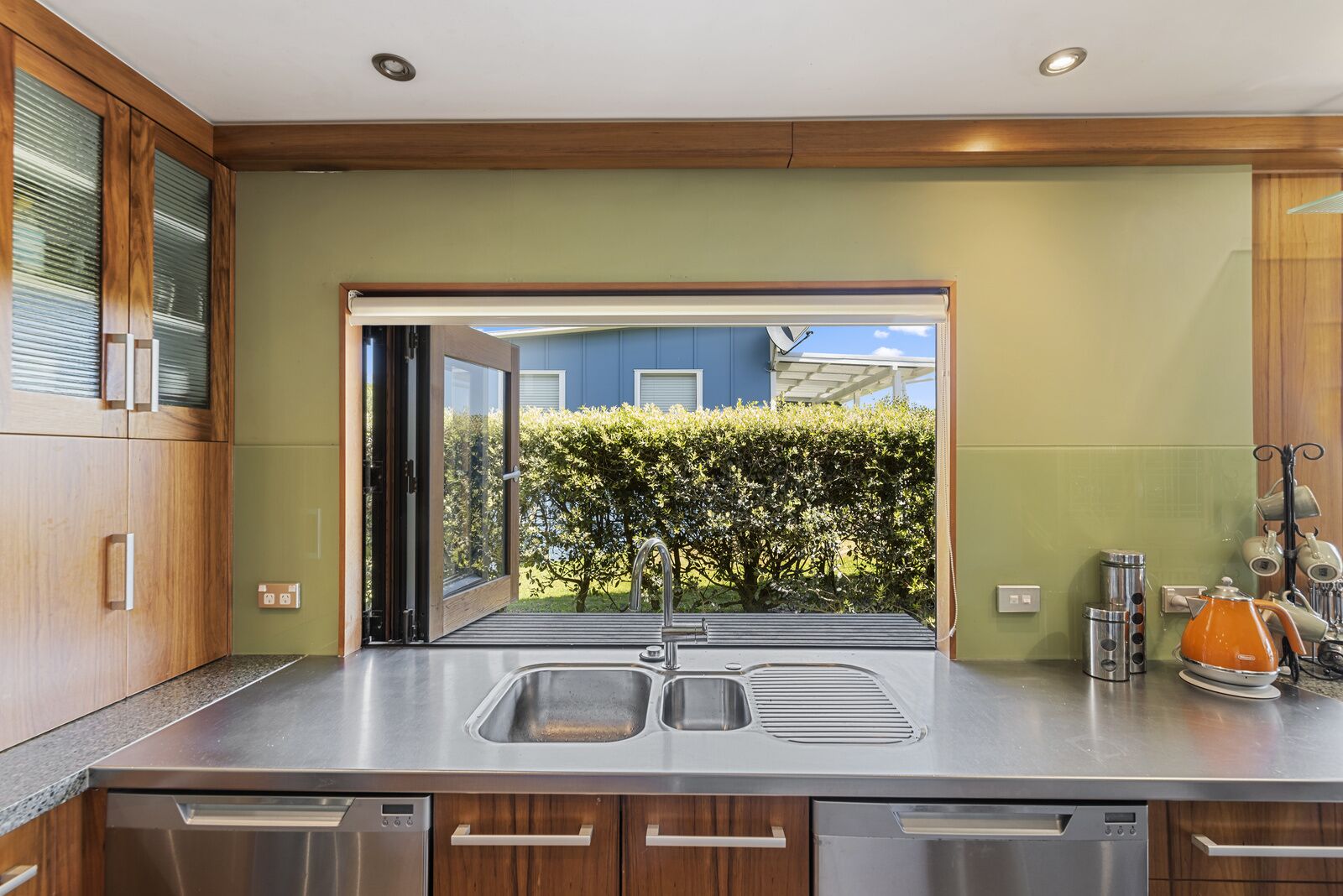 A modern kitchen with a large window, stainless steel appliances, and wooden cabinetry.