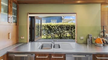 A modern kitchen with a large window, stainless steel appliances, and wooden cabinetry.