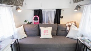 Een moderne woonkamer met een grijze bank, een zwart-wit geruit vloertje en een roze jukebox.