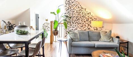 Una sala de estar moderna con un sofá gris, una mesa de centro y un comedor con una mesa de mármol y sillas.
