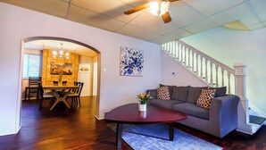 Un salon moderne comprenant un coin repas, un escalier et un ventilateur de plafond.