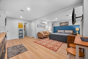 A compact hotel room with a bed, a desk, a chair, a TV, and a bathroom.