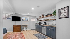Een kleine keuken met een televisie, houten krukken en een eethoek.