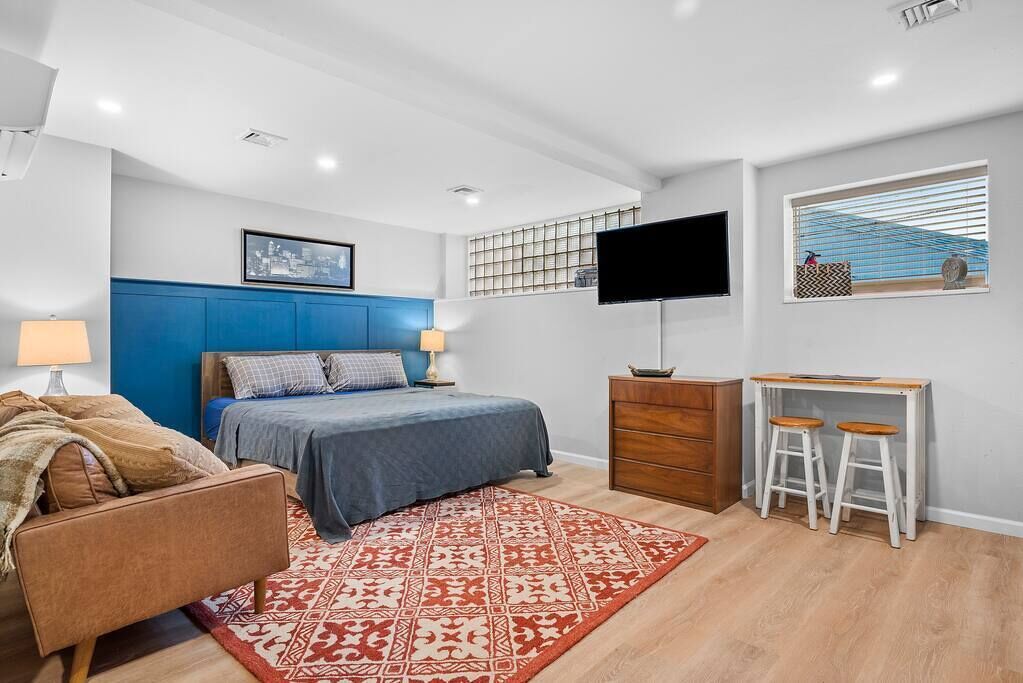 A modern bedroom with a bed, a desk, and a TV.
