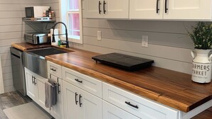 A modern kitchen with white cabinets, a wooden countertop, and a built-in oven. - The Honey Crisp @ Backyard Apple Cottages (FLAT ROCK)