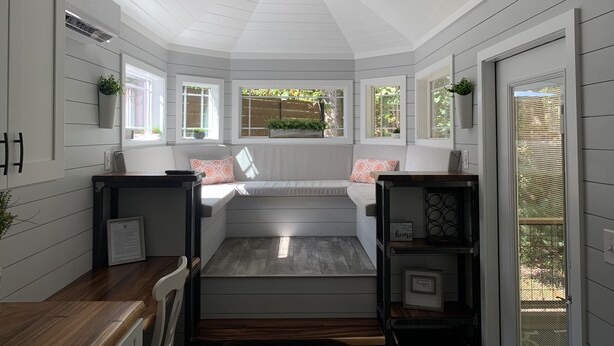 A sunroom with a built-in bench, large windows, and a view of the outdoors. - The Honey Crisp @ Backyard Apple Cottages (FLAT ROCK)