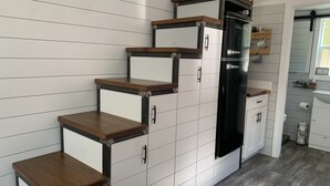A kitchen with white cabinetry, wooden countertops, and a black refrigerator. - The Honey Crisp @ Backyard Apple Cottages (FLAT ROCK)