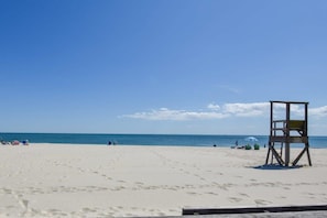 Une plage avec une tour de surveillance, du sable et l’océan.
