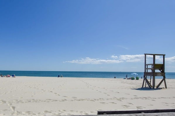 Ein Strand mit einem Rettungsturm, feinem Sand und dem Meer.