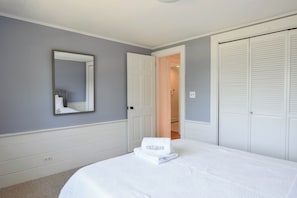 A bedroom with a bed, a mirror, a door, and a closet.