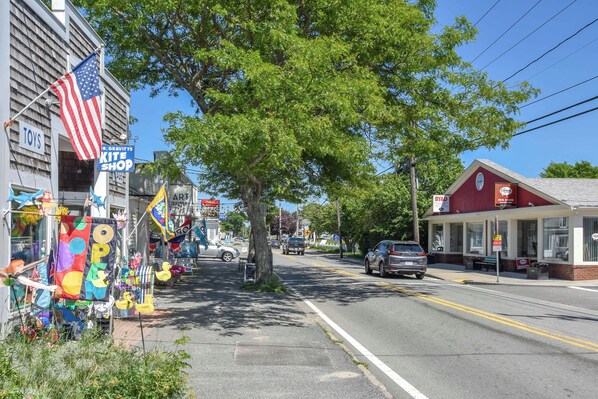 A street with various shops, including a toy store and a pizza shop.