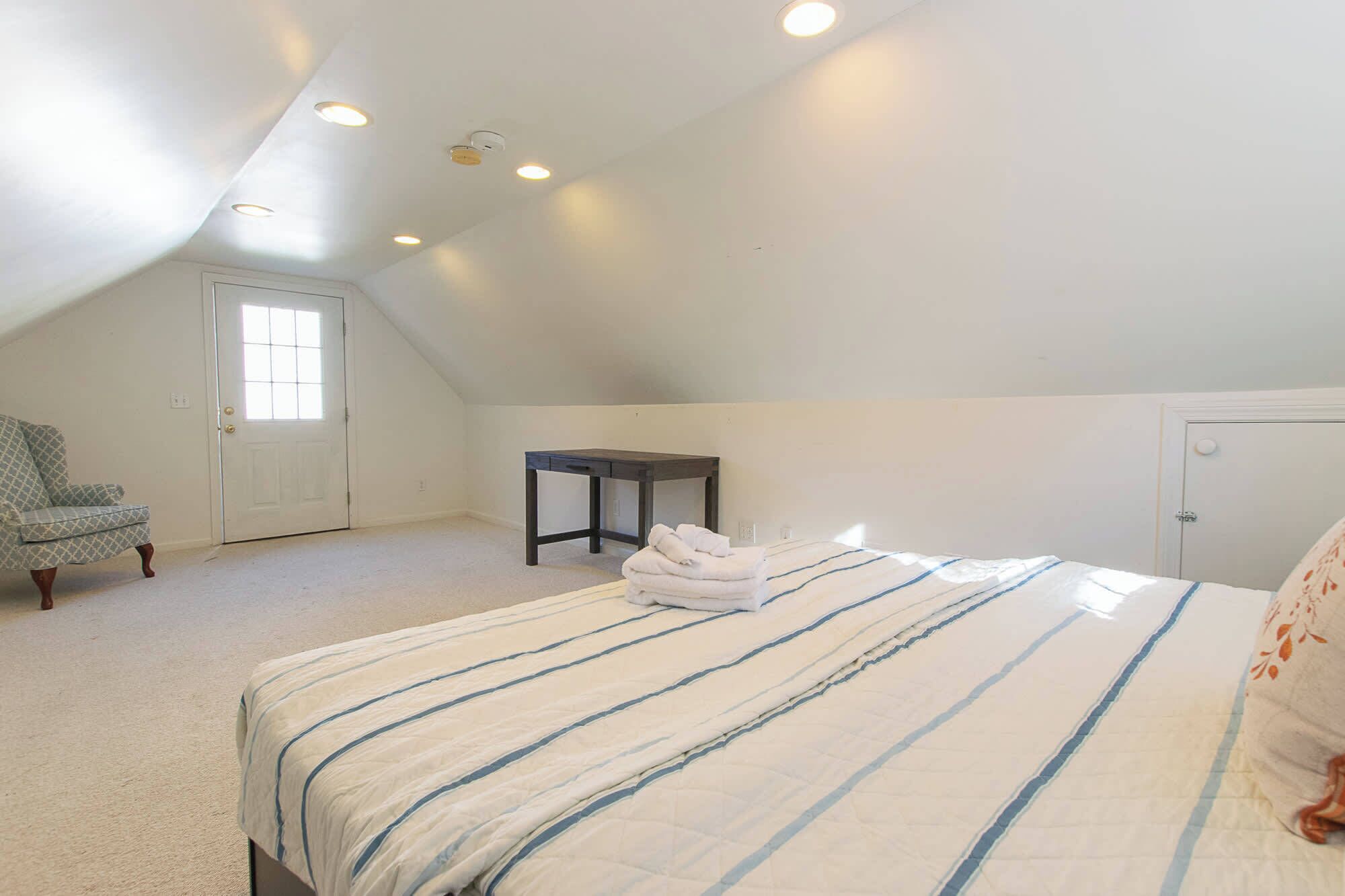 Une chambre à coucher avec un lit, une chaise, une table et une porte.