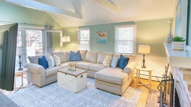 A living room with a sofa, coffee table, lamps, and a fireplace. - Spacious Stone Fire Pit Game Room! (Marstons Mills)