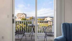 Ein Balkon mit Blick auf Häuser und den Ozean, ein Metallstuhl und ein kleiner Tisch.