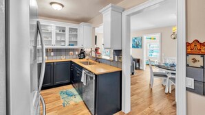 A modern kitchen with white cabinets, a wooden countertop, and a built-in island. - Shady Mango by Duncan Real Estate (Anna Maria)