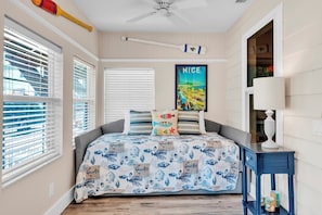 A bedroom with a bed, a ceiling fan, a poster, and a window with blinds. - Shady Mango by Duncan Real Estate (Anna Maria)