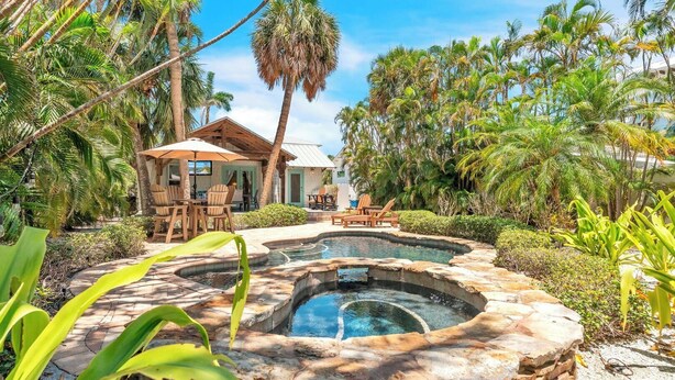 A tropical resort with a pool, lounge chairs, and a dining area. - Shady Mango by Duncan Real Estate (Anna Maria)