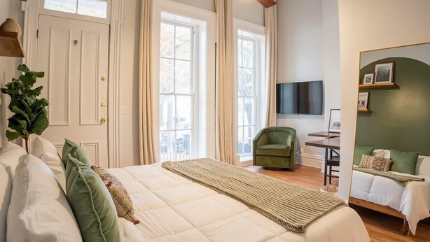 Un dormitorio con cama, escritorio, silla y televisión.