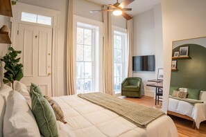 Ein Schlafzimmer mit einem Bett, einem Schreibtisch, einem Sessel und einem Fernseher.