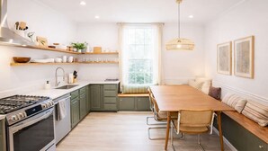 Una cocina moderna con estufa integrada, una mesa de comedor con sillas y una ventana con vistas a la vegetación.