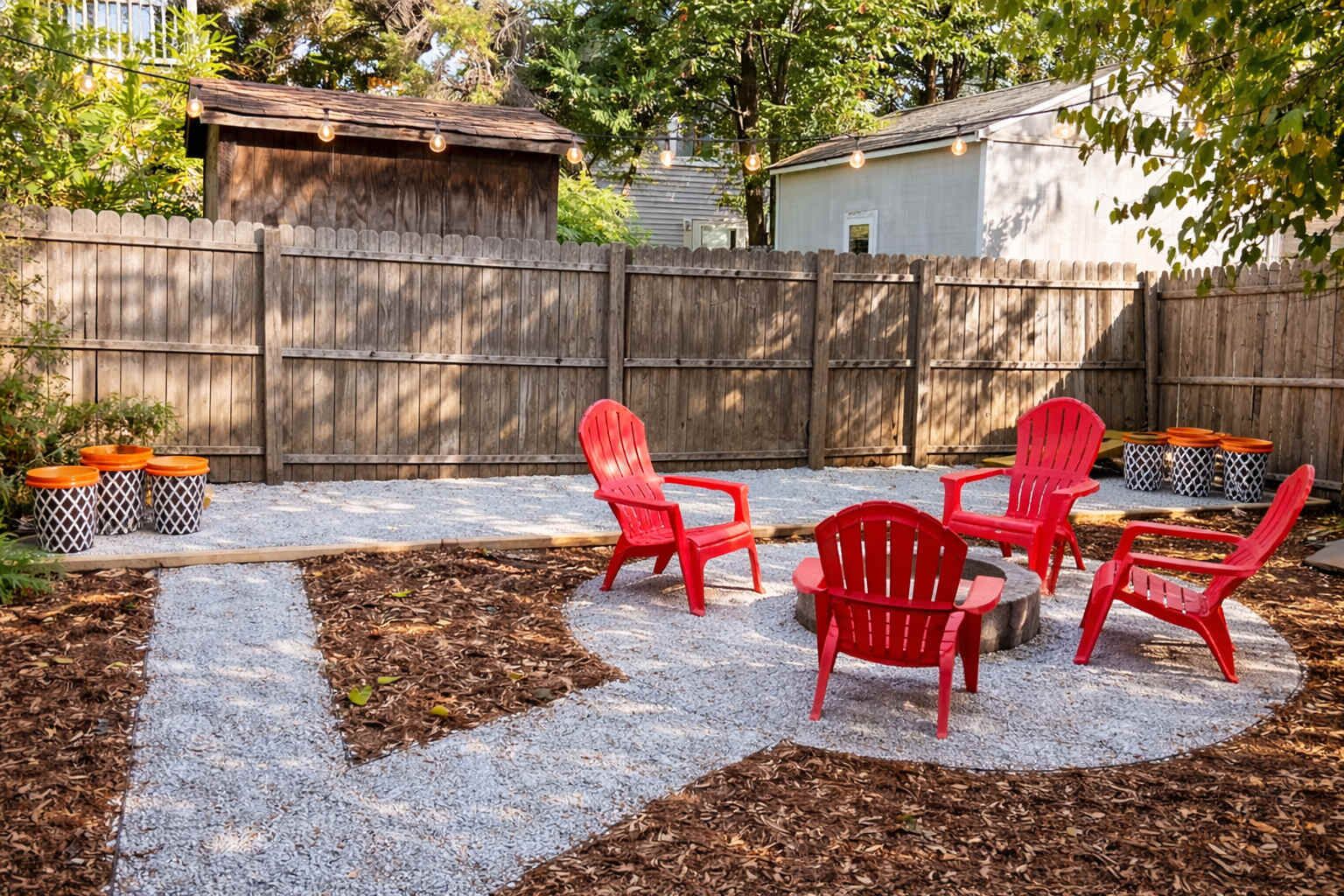 A backyard patio with red Adirondack chairs and outdoor trash bins.