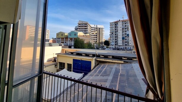 Vista desde una ventana que da a un paisaje urbano con varios edificios, una mezcla de construcciones residenciales y comerciales.