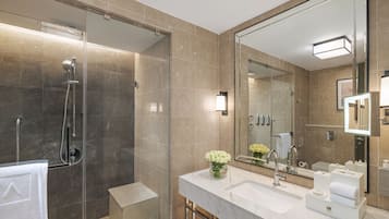 A modern bathroom with a glass-enclosed shower, a large mirror, and a marble vanity.
