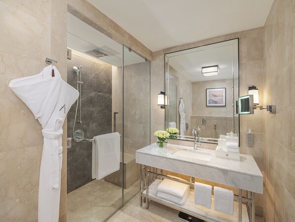 Une salle de bain moderne avec une douche à parois de verre, un grand miroir et un meuble-lavabo recouvert de carreaux de marbre.