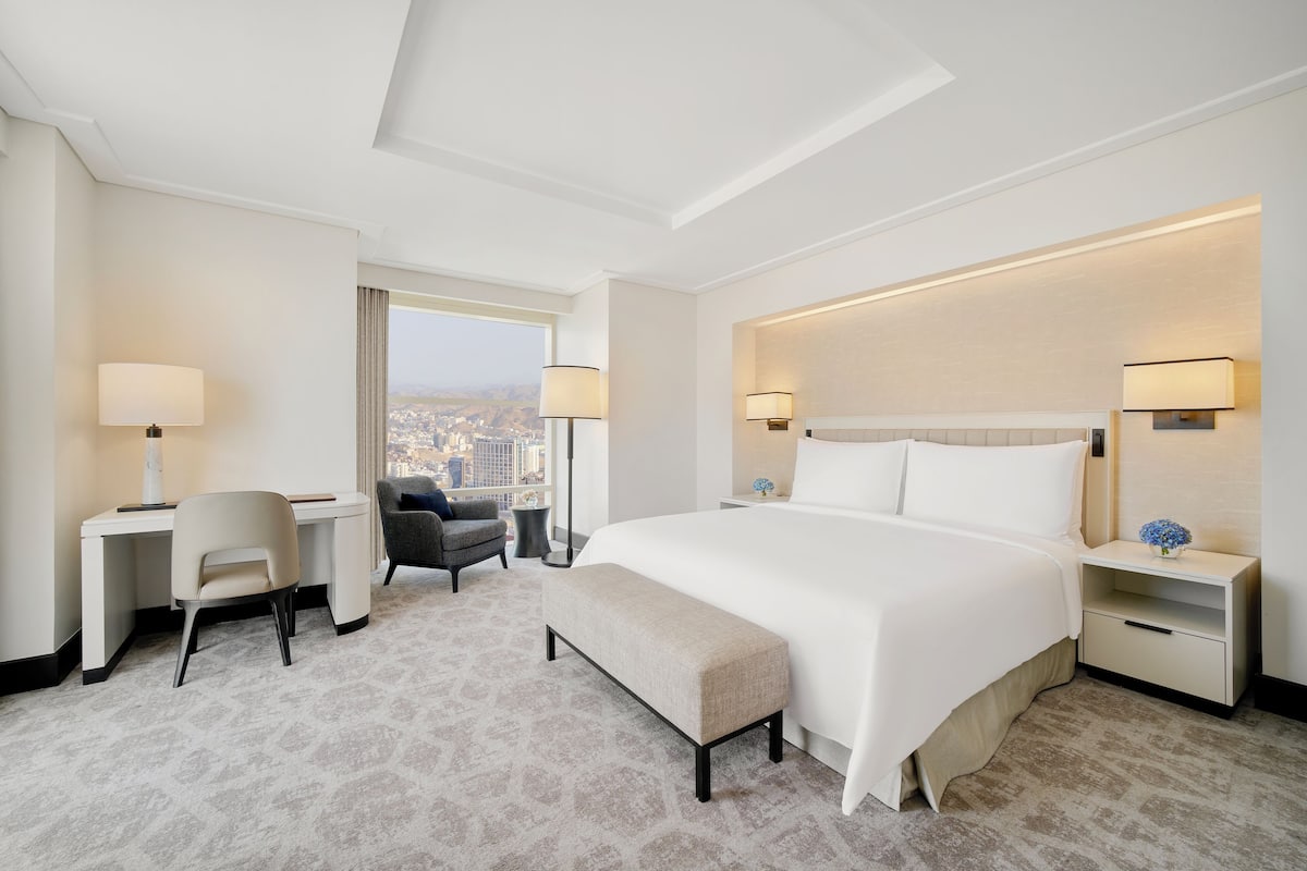 Une chambre d’hôtel avec un grand lit, un bureau, une chaise et une vue sur la ville.