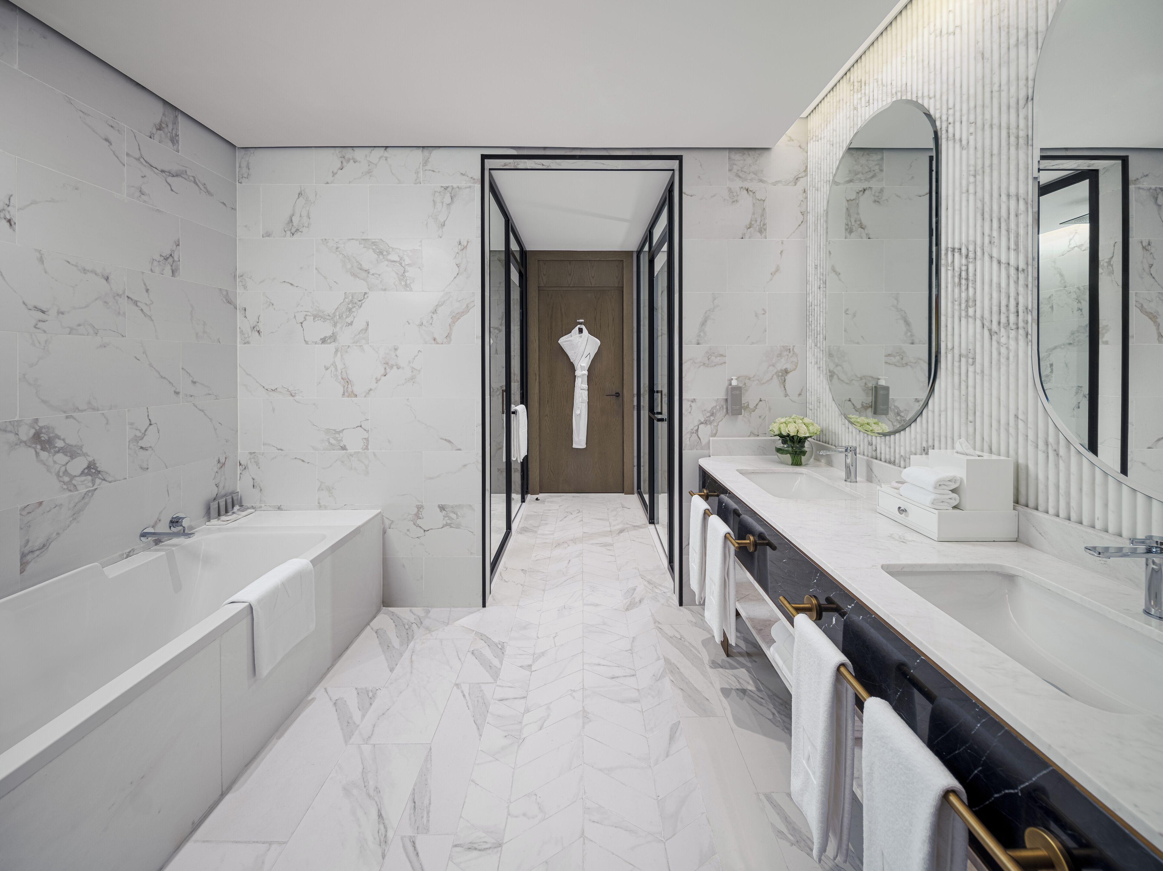 A modern bathroom with a large mirror, a bathtub, and a shower.
