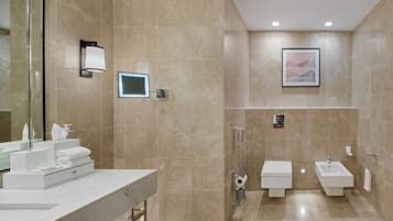 A modern bathroom with a vanity, a shower, a toilet, and a bidet.