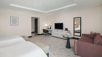 Una habitación de hotel con cama, escritorio con televisor, sofá y espejo.