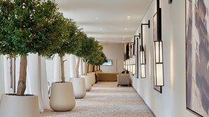 A hallway with potted trees, a sofa, and framed pictures on the walls. - Address Jabal Omar Makkah (Makkah)