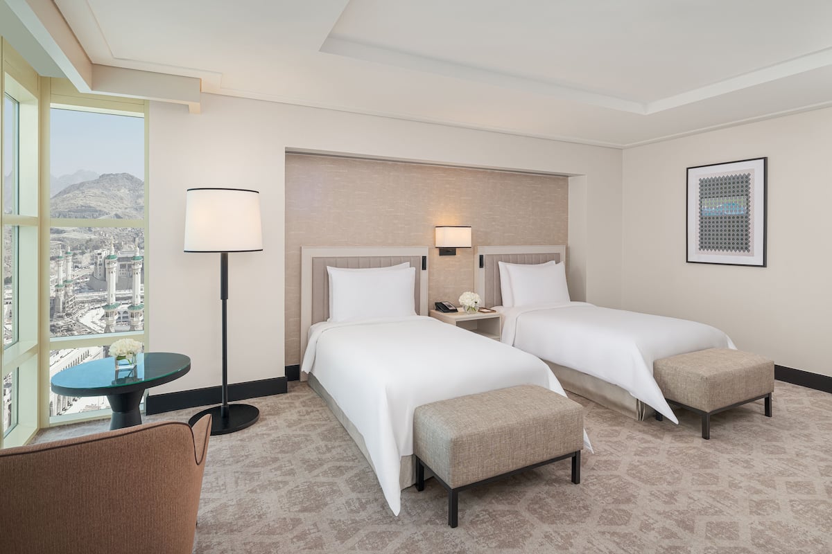 Une chambre d’hôtel avec deux lits, un bureau, une chaise et une vue sur le paysage urbain.