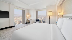 A hotel room with a large bed, a desk, two chairs, a TV, and two lamps. - Address Jabal Omar Makkah (Makkah)