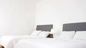 Ett hotellrum med två sängar, en takfläkt och ett nattduksbord med en lampa.
