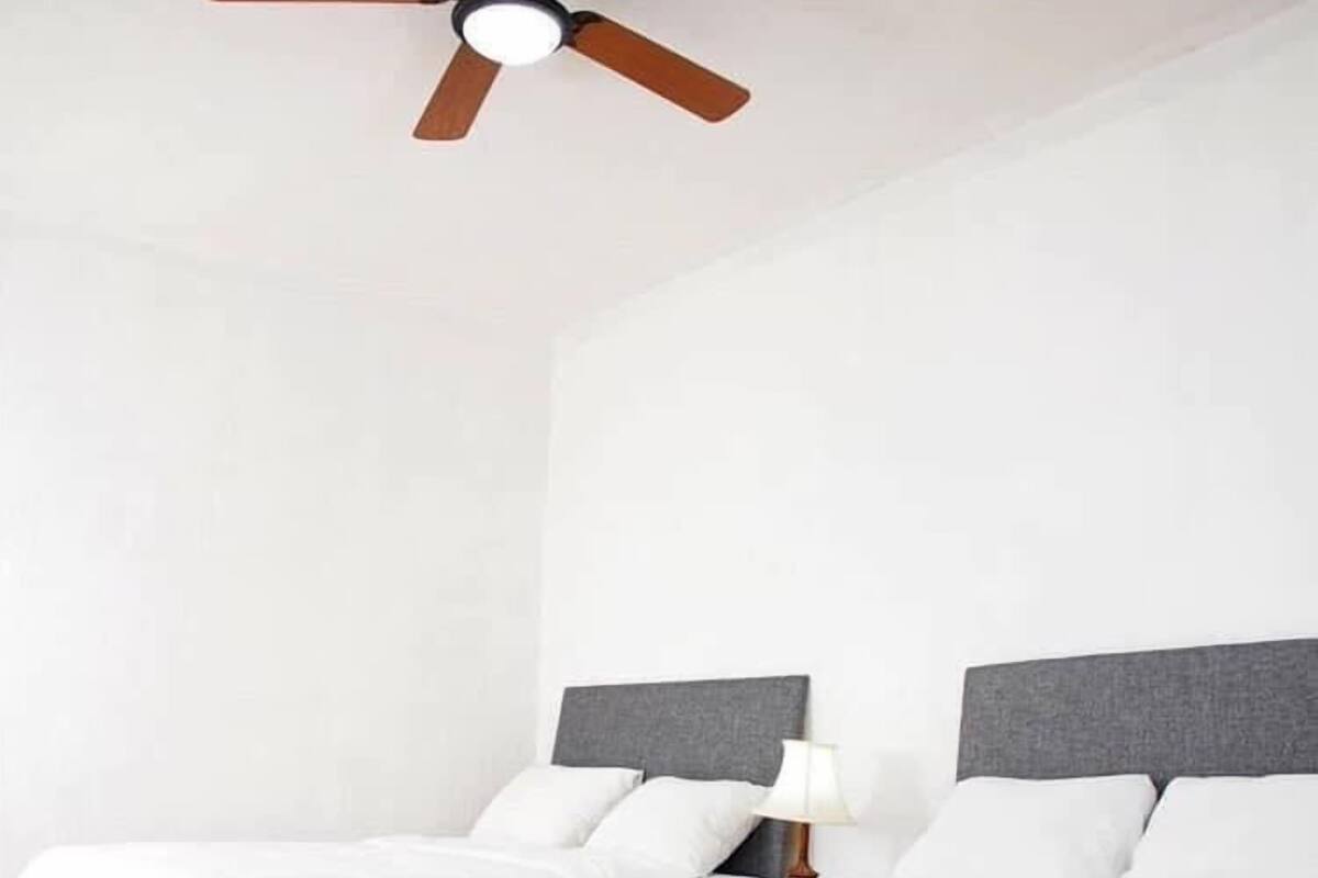 A hotel room with two beds, a ceiling fan, and a nightstand with a lamp.