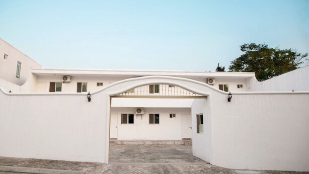 Un edificio bianco con un arco centrale, diverse finestre e un tetto piano.