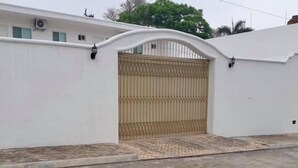 Un muro bianco con un cancello in metallo e un piccolo gradino che vi conduce.