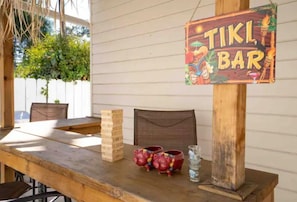 A wooden table with a tiki bar sign, two pig-shaped mugs, and a glass of water.