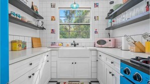 A modern kitchen with white cabinets, a blue stove, and a window with a view of greenery. - Darling Paso Cottage 2blks DT/2 King Bds/Firept/ (Paso Robles)