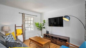 A living room with a sofa, a coffee table, a TV, and a lamp. - Darling Paso Cottage 2blks DT/2 King Bds/Firept/ (Paso Robles)
