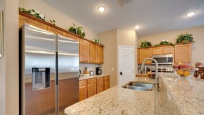 Una cocina moderna con electrodomésticos de acero inoxidable, encimeras de granito, armarios de madera y un microondas integrado.