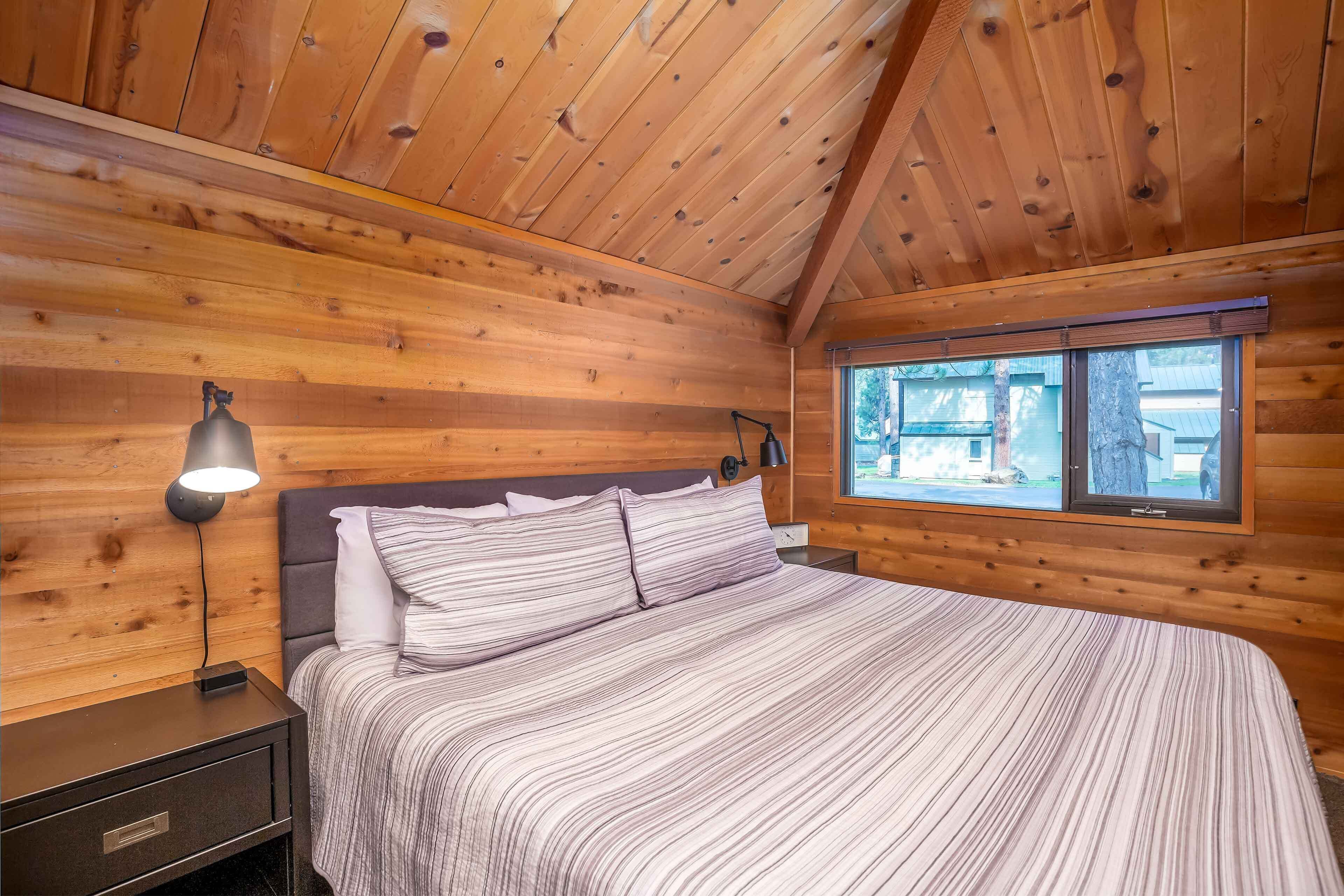 Ein Schlafzimmer in einer Holzhütte mit einem Bett, Nachttischen und einem Fenster.