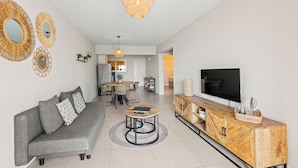 A modern living room with a grey sofa, wooden coffee table, and a TV on a wooden cabinet.