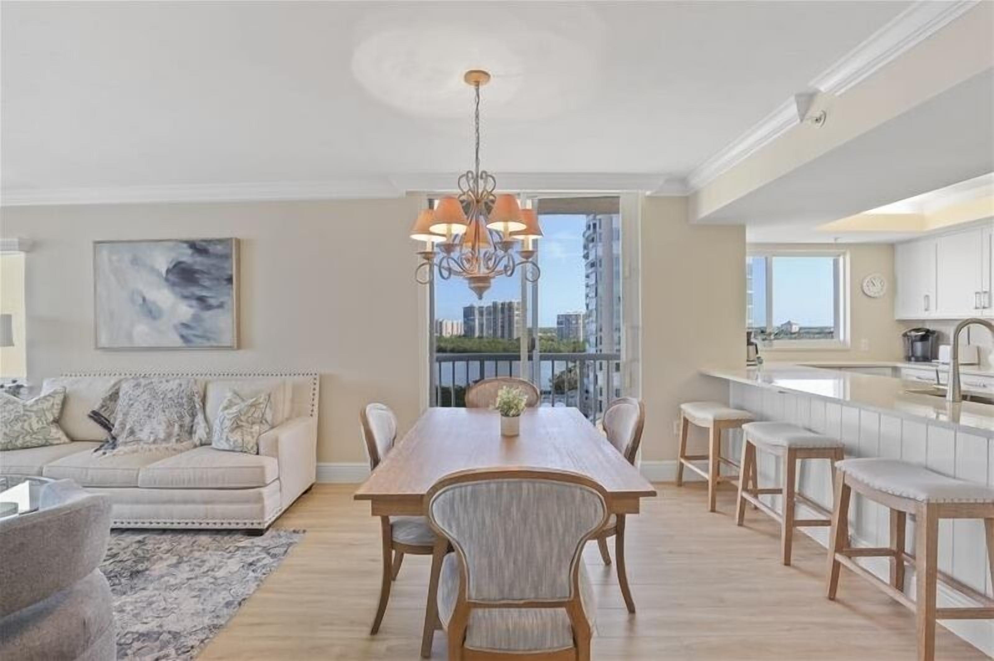 A spacious living room with a dining area, a sofa set, and a view of the city through large windows.